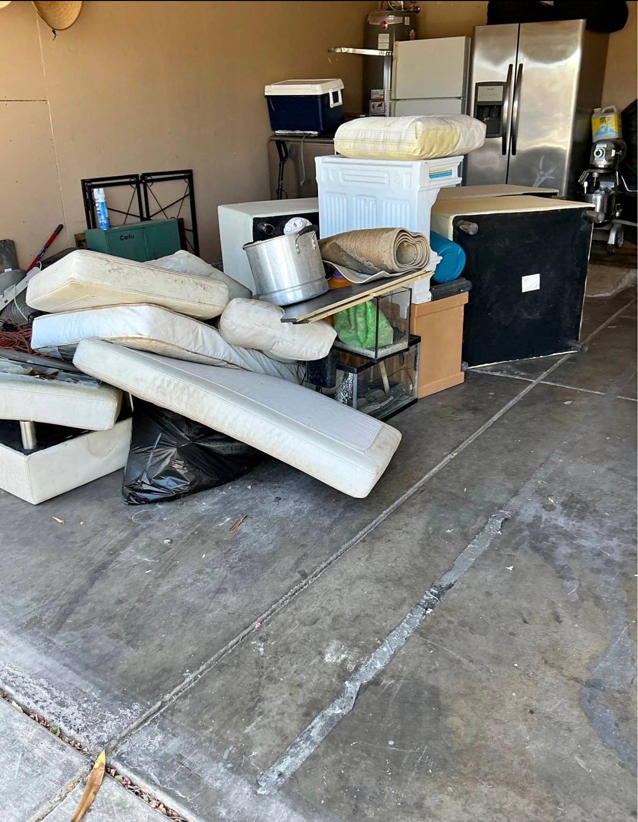 Garage cleanout with appliances and mattresses staged for haul-away